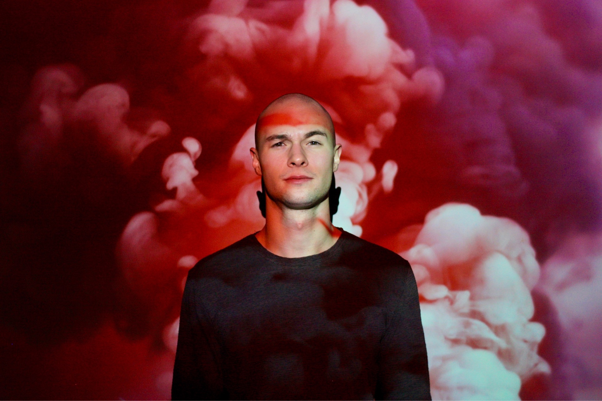 A man standing in front of a vibrant red & purple smoke cloud.