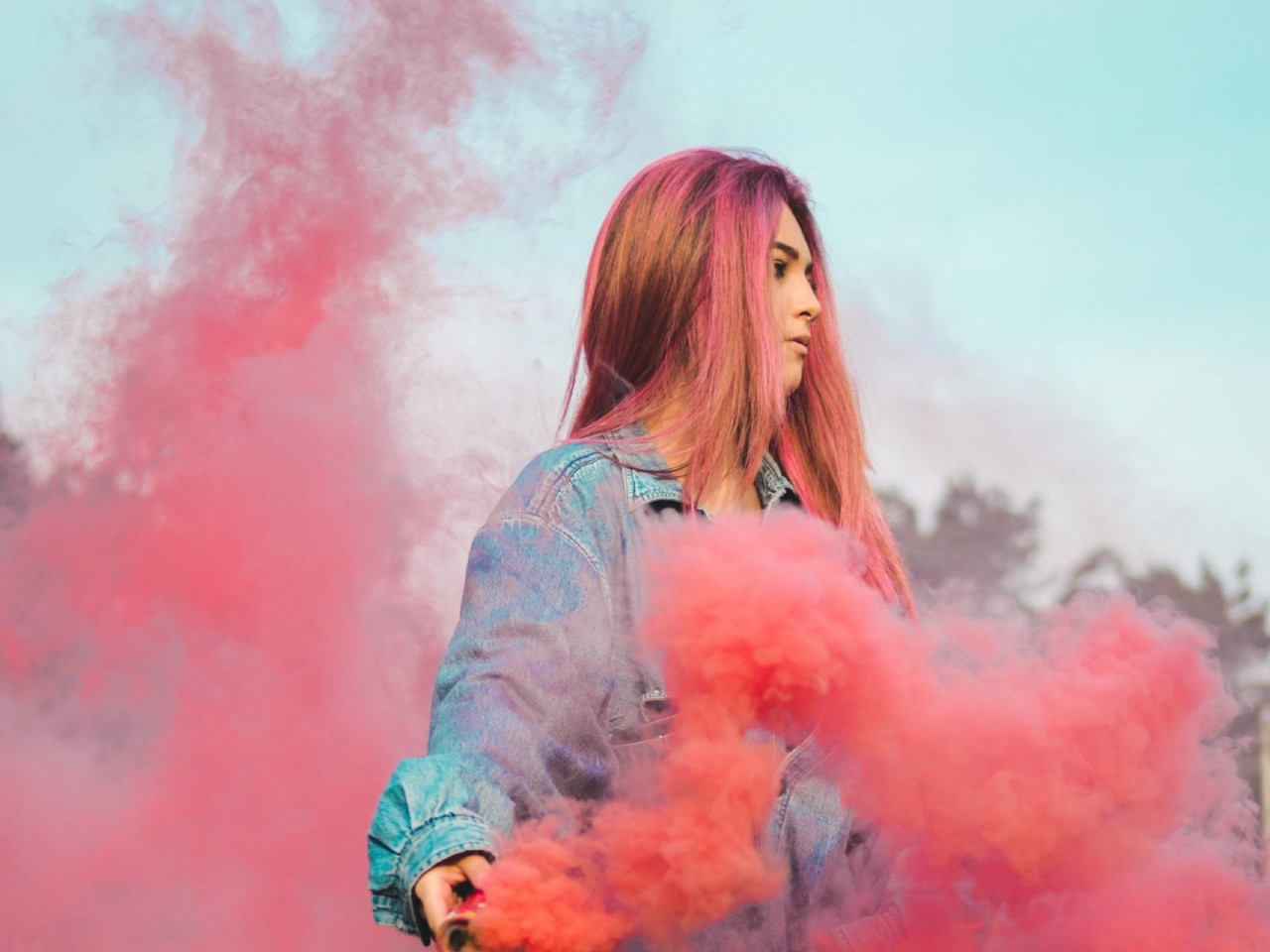 A woman holding pink smoke in her hand.