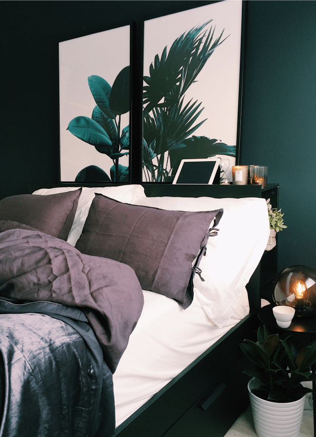 Bedroom featuring bed, nightstand, & wall painting of a plant. A showcase of Elle's apartment's sleek design.