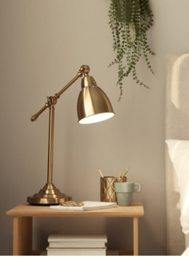 A bedside lamp with a small plant on top. Sample bedroom decor you can do at Elle luxury apartments.